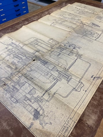 A technical drawing of engine compontents lies across a table.
