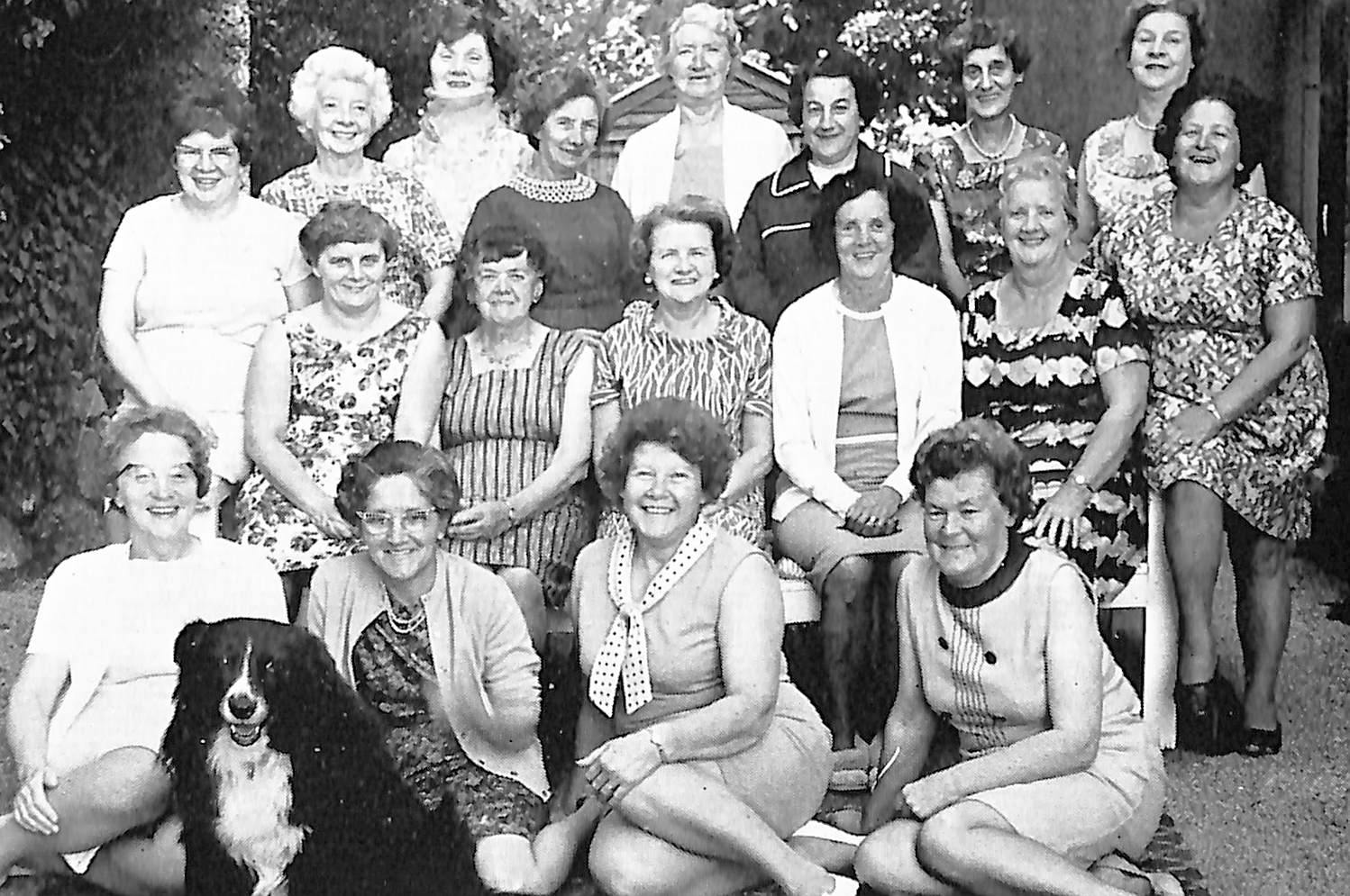 Photograph showing a group of visitors to Inwood pose with one of the house’s dogs. Black & White.