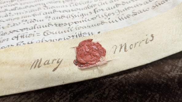 A close-up shot of a wax seal. The name 'Mary Morris' is inscribed around it.