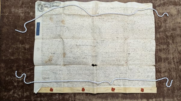 A wide shot of the marriage settlement between Mary Morris and John Wigston. Snake weights flatten the document at the top and bottom.