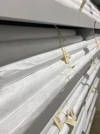 Several rehoused rolls on an archive shelf. They appear as tubes wrapped in Tyvek sheeting, white in colour.