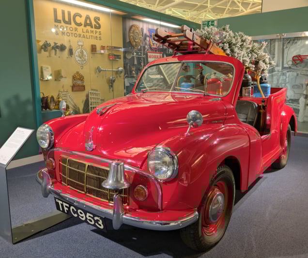 A red classic fire engine with a Christmas tree attached to a ladder on the back