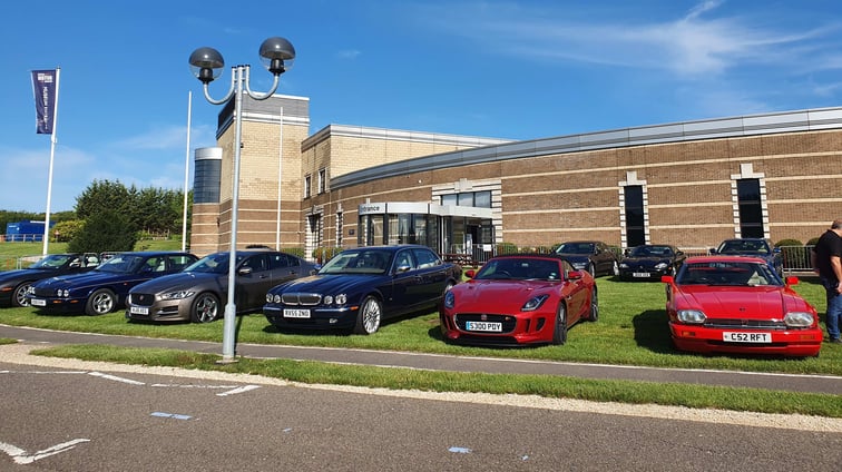 A number of various Jaguar Cars parked on a grass area in front of the British Motor Museum