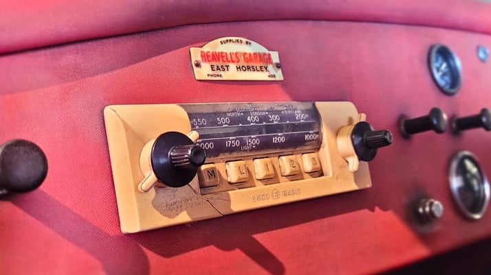 Photo of the red dash of a car with an old style radio